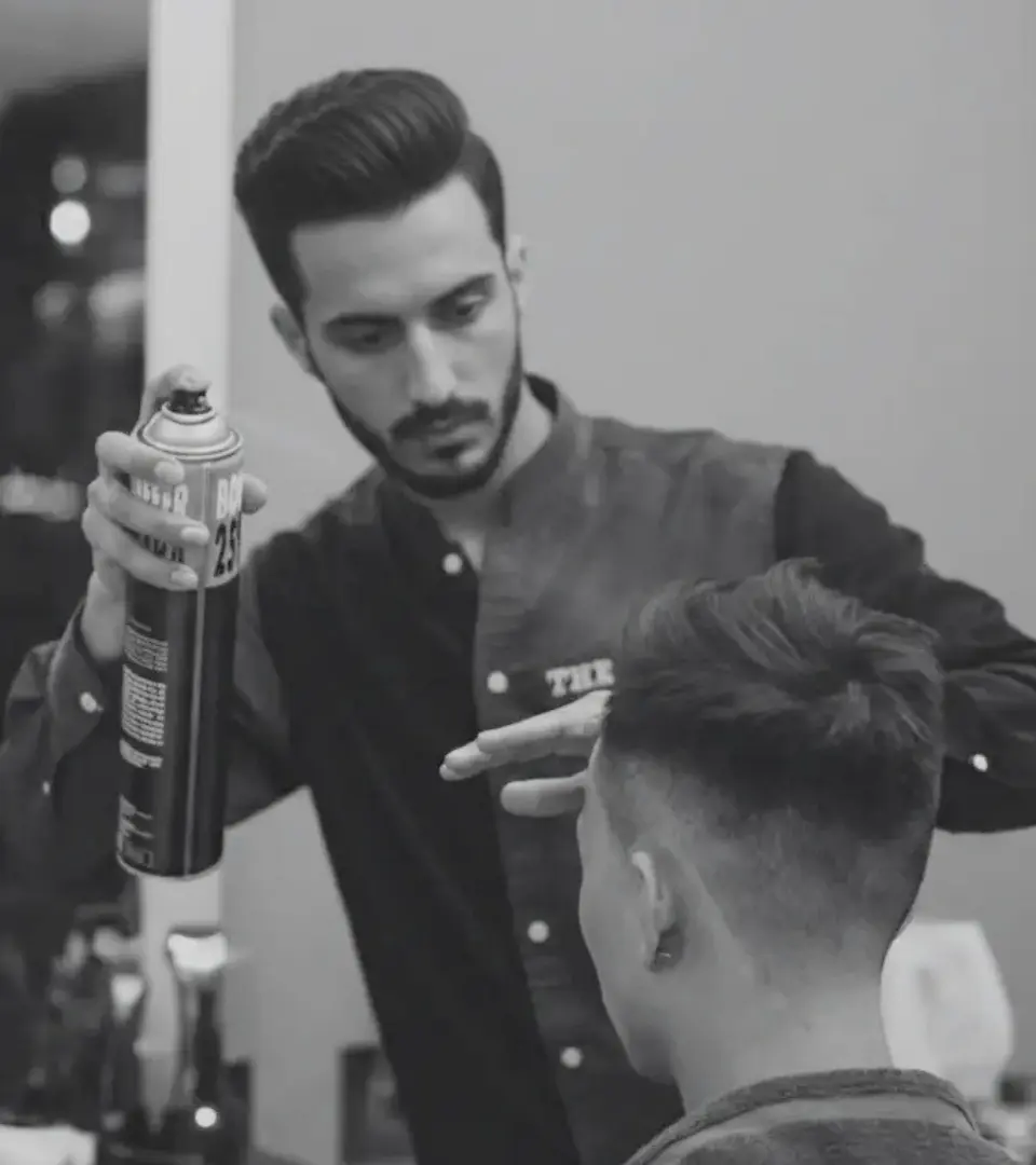 Barber applying product while styling a client in black and white