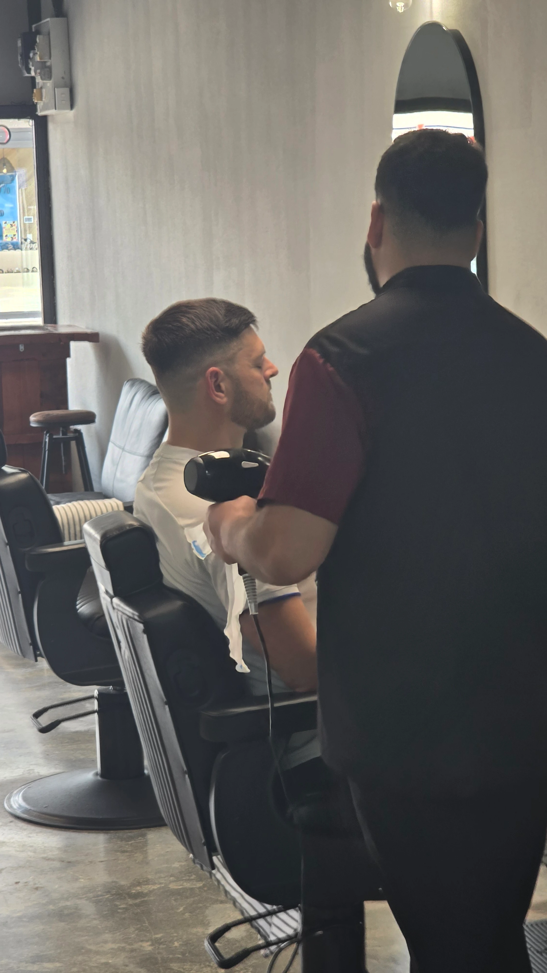 Barber blow-drying a client in the lounge